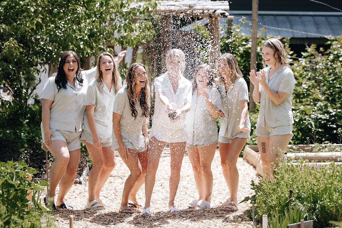 bridal party popping champagne at pebble cove venue